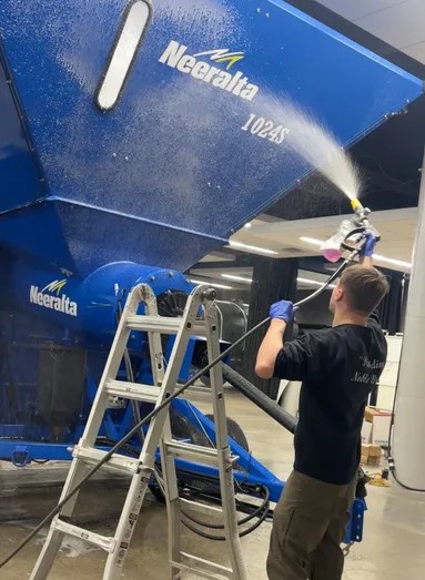 Noble Detailing technician hand-polishing a sedan in a driveway